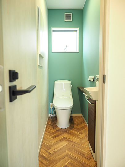 グリーンのクロスとヘリンボーンの床が落ち着くトイレ